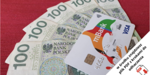 Kilka banknotów o nominale 100 złotych ułożonych w wachlarz na czerwonej powierzchni, z białą kartą debetową mBank Visa umieszczoną na górze. Polska notatka w rogu wspomina o pliku PDF z krokami do wykonania.