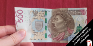 Ręka trzymająca polski banknot 500-złotowy z portretem postaci historycznej. W rogu czarny ukośny baner wyświetla komunikat w języku polskim o pliku PDF z ikoną dokumentu PDF.