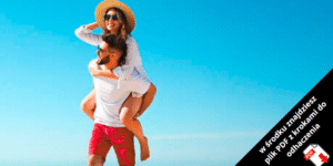 Uśmiechnięta kobieta w kapeluszu i okularach przeciwsłonecznych jedzie na plecach mężczyzny na plaży pod czystym, błękitnym niebem. W prawym dolnym rogu znajduje się polski tekst i ikona PDF.