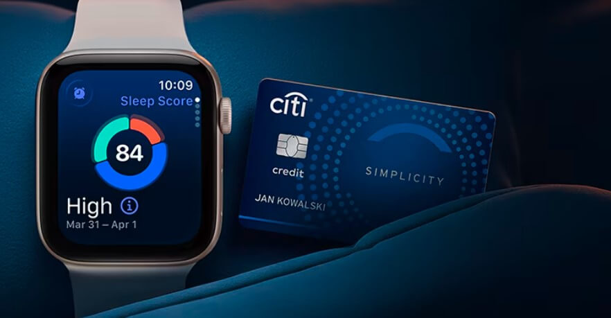 Smartwatch wyświetla wynik snu 84 wraz z datą, obok niebieskiej karty kredytowej Citi Simplicity spoczywającej na ciemnej powierzchni.