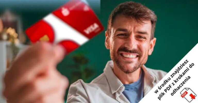 Uśmiechnięty mężczyzna trzyma czerwono-białą kartę VISA w kierunku kamery. W rogu widnieje polski tekst: 